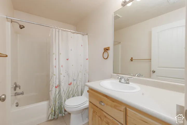 Bathtub with shower, toilet, wood-finish vanity with countertop, and integrated sink