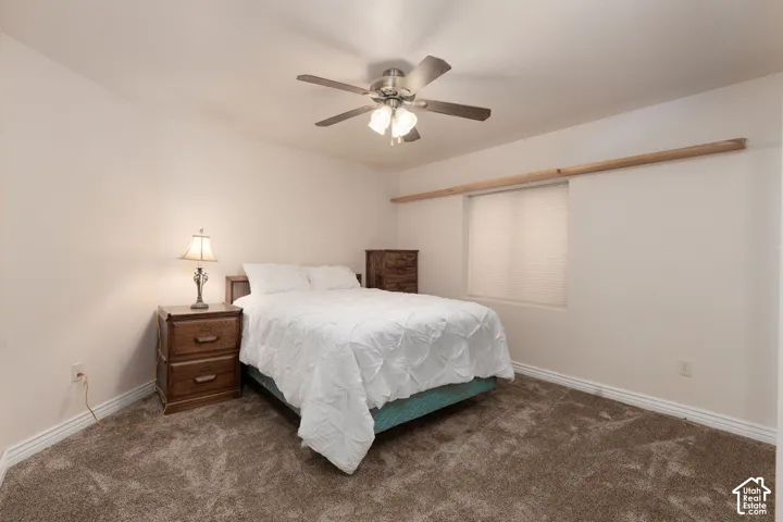 Bedroom 5 with neutral wall paint, textured carpeting, window with blinds, and a ceiling fan with integrated lighting