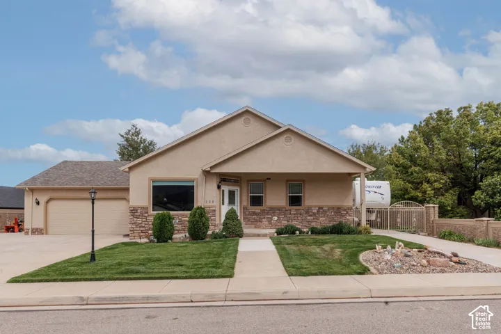 Stucco exterior with stone accents, attached two-car garage, concrete driveway, front walkway, and a decorative rock garden