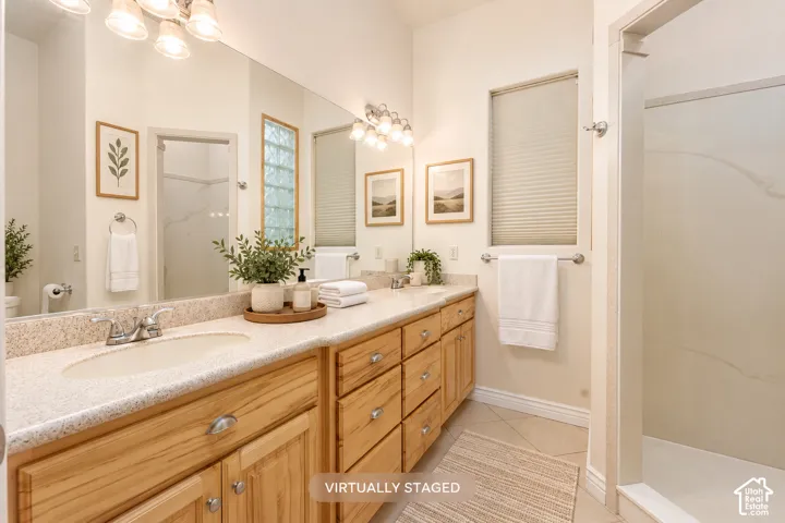 Primary bathroom with dual vanity with wood-finish cabinetry, integrated sinks, and polished chrome fixtures