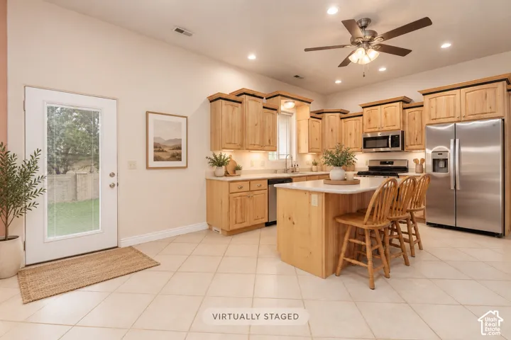 Kitchen featuring light wood cabinetry, stainless steel appliances, a center island with countertop seating, and recessed lighting