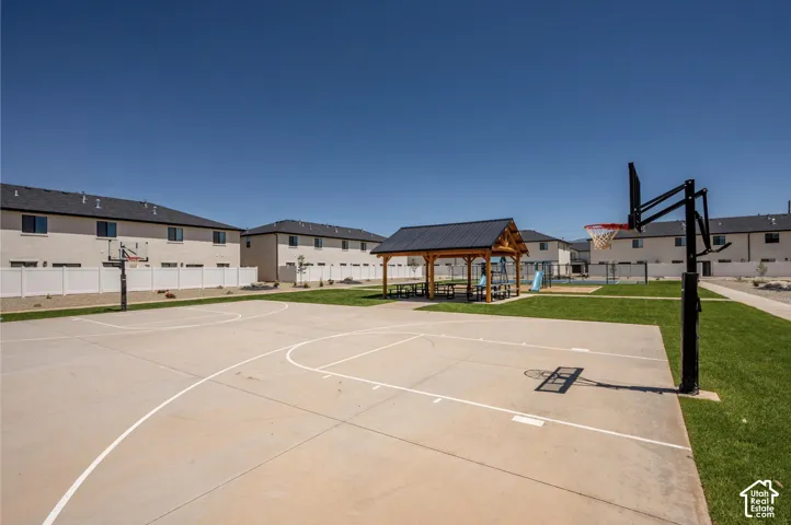 Outdoor concrete basketball court with two hoops, central gazebo, and manicured green spaces