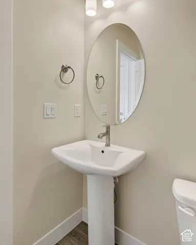 Pedestal sink with a polished chrome faucet, oval mirror, and wall-mounted light fixtures