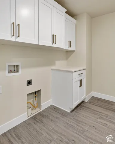 White shaker cabinetry with brushed bronze hardware, light-toned countertop, and wood-finish flooring
