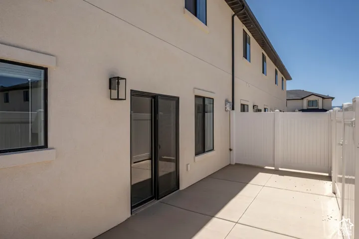 Private patio with a concrete surface, enclosed by a white privacy fence