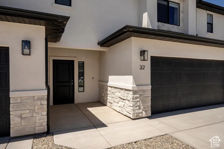 Stucco exterior with stone accenting, black garage door, and modern exterior lighting