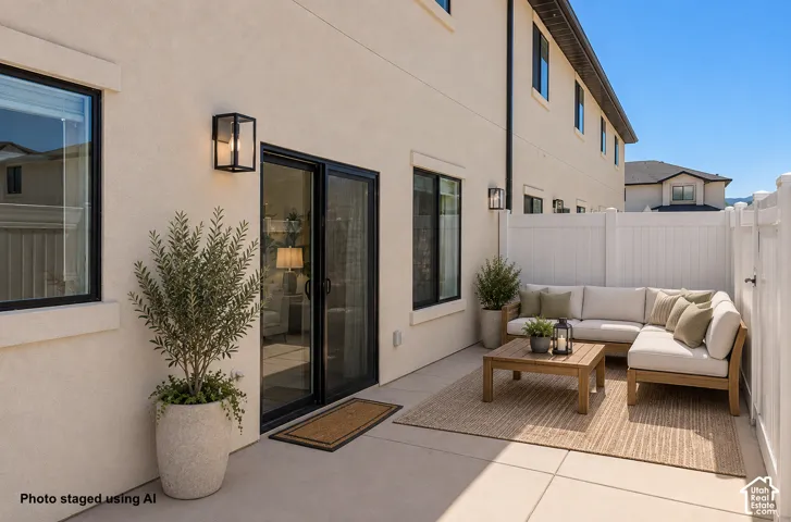 Concrete patio with a privacy fence, exterior wall sconces, and a sliding glass door
