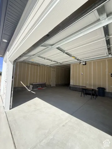 Spacious garage with a concrete floor, overhead lighting, and a white paneled garage door