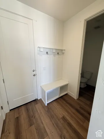 Entryway featuring wood-finish flooring, white paneled door, and a built-in bench with storage and coat hooks