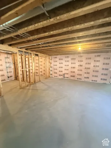 Open-concept lower level with concrete flooring, framed interior walls, and exposed ceiling joists