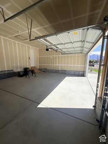 Spacious garage with concrete flooring, automatic overhead door, and a dedicated entry door