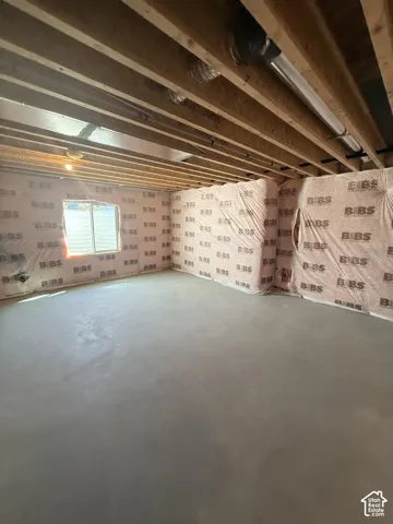 Unfinished basement with exposed wood joists, concrete flooring, and insulated walls