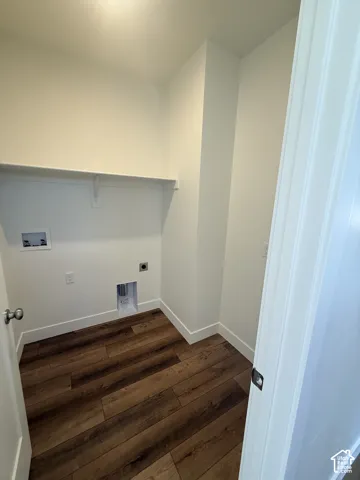 Laundry area featuring wood-finish flooring, white walls, and a built-in shelf