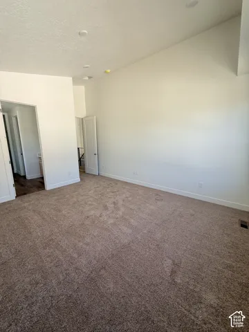 Recessed lighting, vaulted ceiling, white walls, and brown carpeting