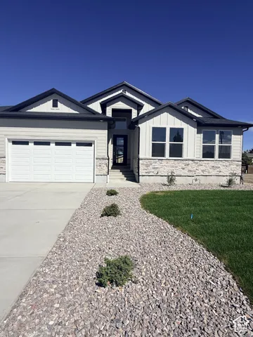 Contemporary exterior featuring light-colored siding, dark trim, a prominent entry, and an attached two-car garage