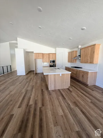 Expansive kitchen featuring wood-finish cabinetry, a large center island with a light-toned countertop, and recessed lighting