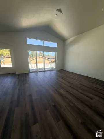 Vaulted ceiling with a recessed light fixture, expansive wood-finish flooring, and large sliding glass doors providing outdoor access