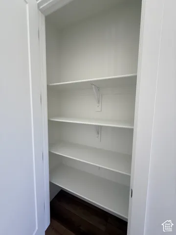 Integrated shelving system with multiple white shelves and dark wood-finish flooring