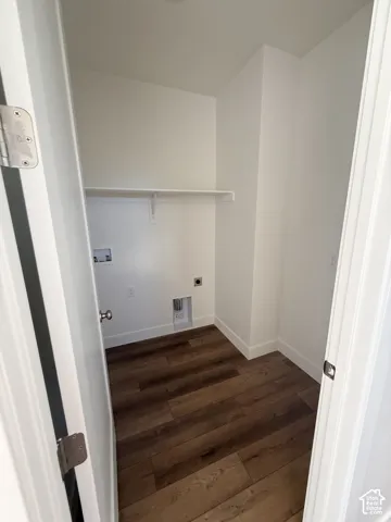 Laundry area with wood-finish flooring, white walls, and a single wall-mounted shelf