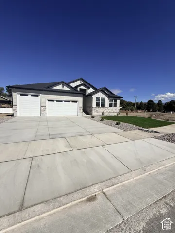 Contemporary home exterior featuring a two-car garage, stone and horizontal siding accents, multiple gabled rooflines, and a concrete driveway