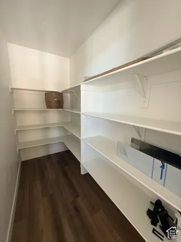 White shelving with ample storage, wood-finish flooring, and white walls