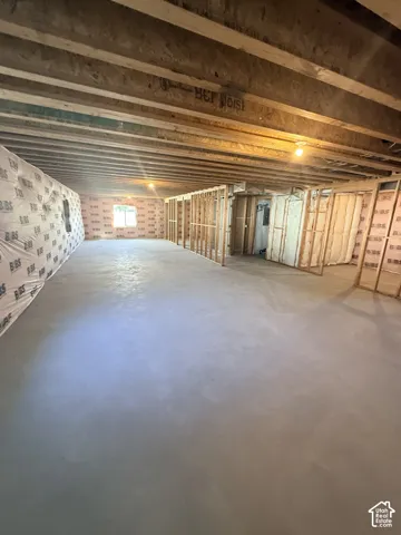 Unfinished basement with exposed wood joists, concrete flooring, and framed interior walls