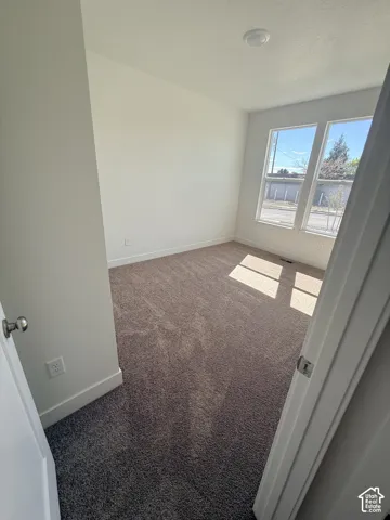 Recessed ceiling light, double window unit, dark carpeting, and white wall finishes