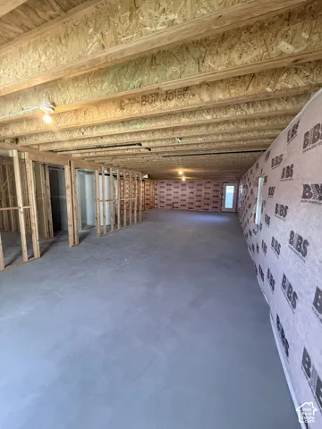 Expansive unfinished space featuring concrete flooring, exposed wood joists, and framed interior walls