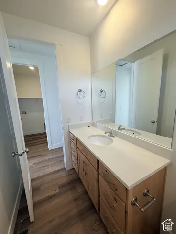 Vanity featuring a light-toned countertop, integrated sink, and wood-finish cabinetry