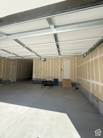 Expansive concrete flooring with a white overhead garage door and interior access doors