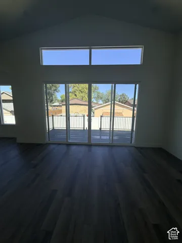 Vaulted ceiling, wood-finish flooring, sliding glass doors, upper transom windows, and an outdoor deck
