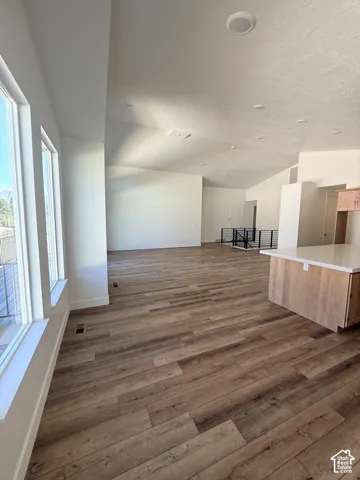 Expansive open-concept living space with wood-finish flooring, recessed lighting, and a kitchen island featuring a light-toned countertop