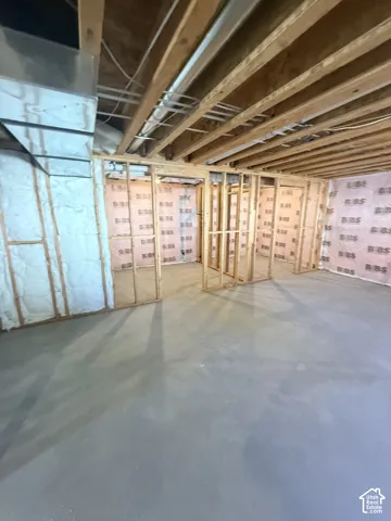 Unfinished basement featuring exposed wood joists, framed interior walls, insulated exterior walls, and a concrete floor