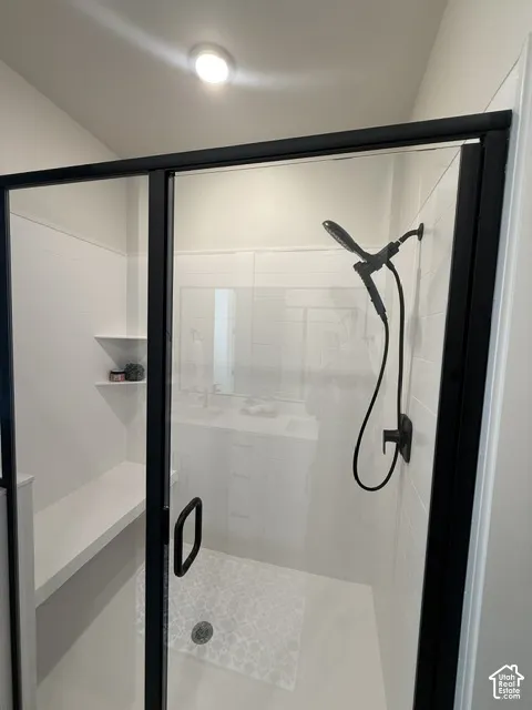 Shower enclosure with matte black framing, white subway tile surround, built-in bench, and patterned floor tile