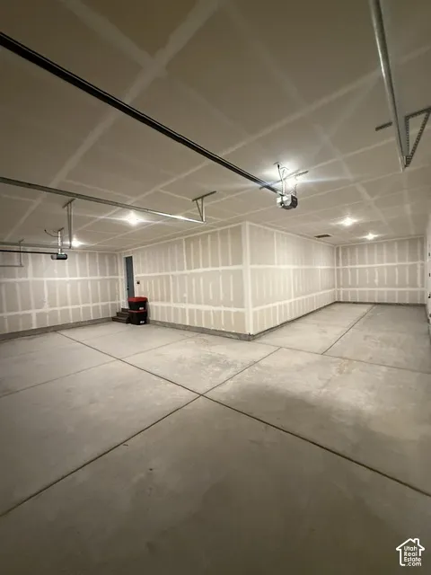 Spacious garage with exposed drywall, concrete flooring, and multiple recessed ceiling lights