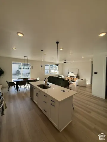 Open-concept living space featuring wood-finish flooring, recessed lighting, and a kitchen island with a built-in sink