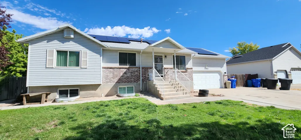 Split-level residence featuring a covered entry, vinyl siding, and brick veneer accents