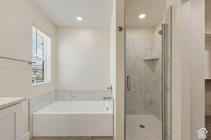 Recessed lighting illuminates the tiled shower with glass enclosure, a built-in shelf, and hexagonal floor tiles