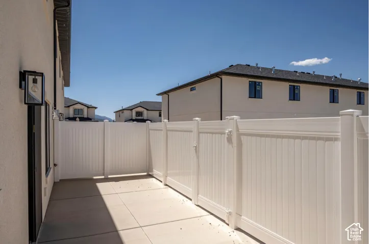 Private side yard featuring a concrete patio, vinyl fencing, and an exterior wall light fixture