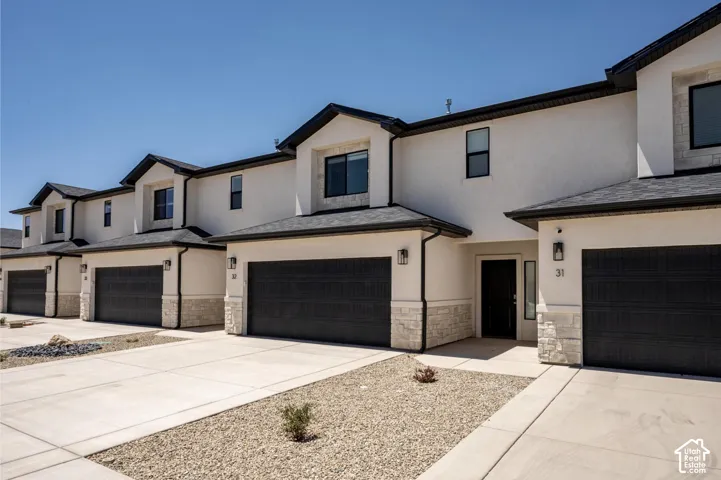 Stucco exterior with stone accents, dark garage doors, and black roofing
