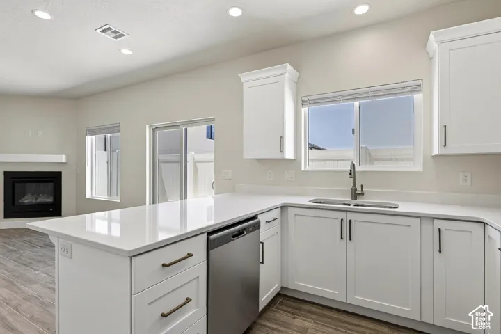 Contemporary kitchen featuring white cabinetry, light-colored countertops, stainless steel appliances, and a gas fireplace