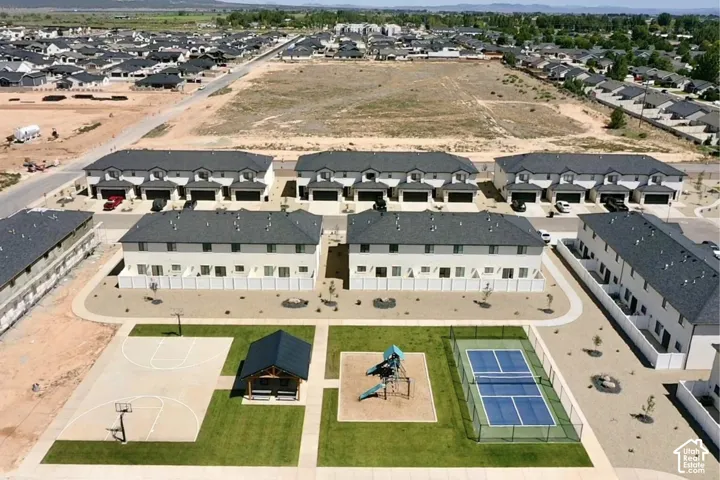 Modern townhomes featuring attached garages, private fenced patios, and communal recreational amenities including a basketball court, covered pavilion, and tennis court