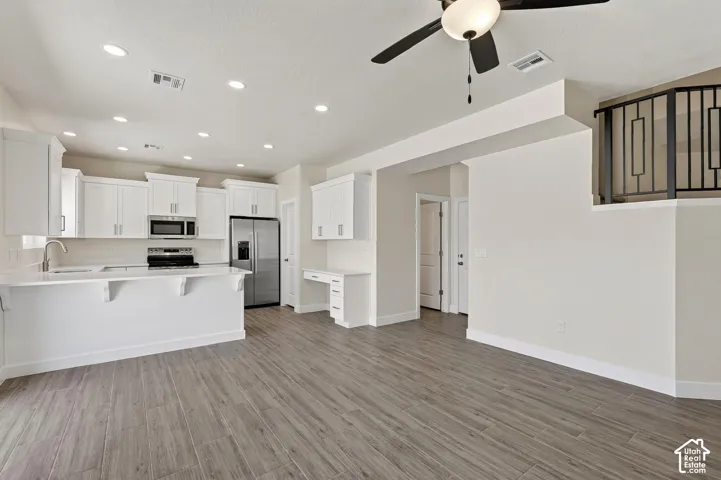 Open-concept living area featuring wood-finish flooring, recessed lighting, and a ceiling fan