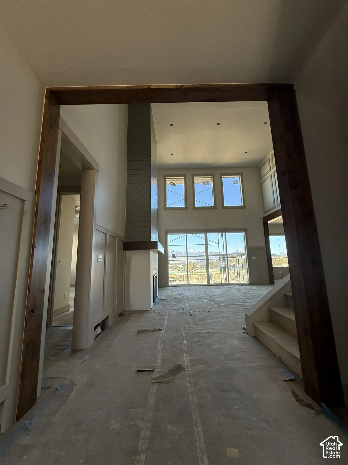 Vaulted ceilings with recessed lighting, timber-framed entryway, floor-to-ceiling fireplace surround, and expansive glass paneled windows