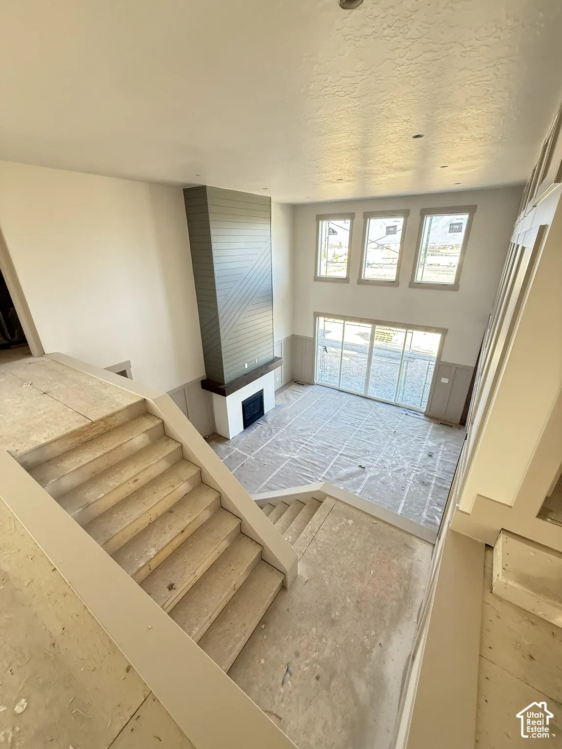Two-story living area featuring a fireplace with shiplap detailing, tall windows, and sliding glass doors