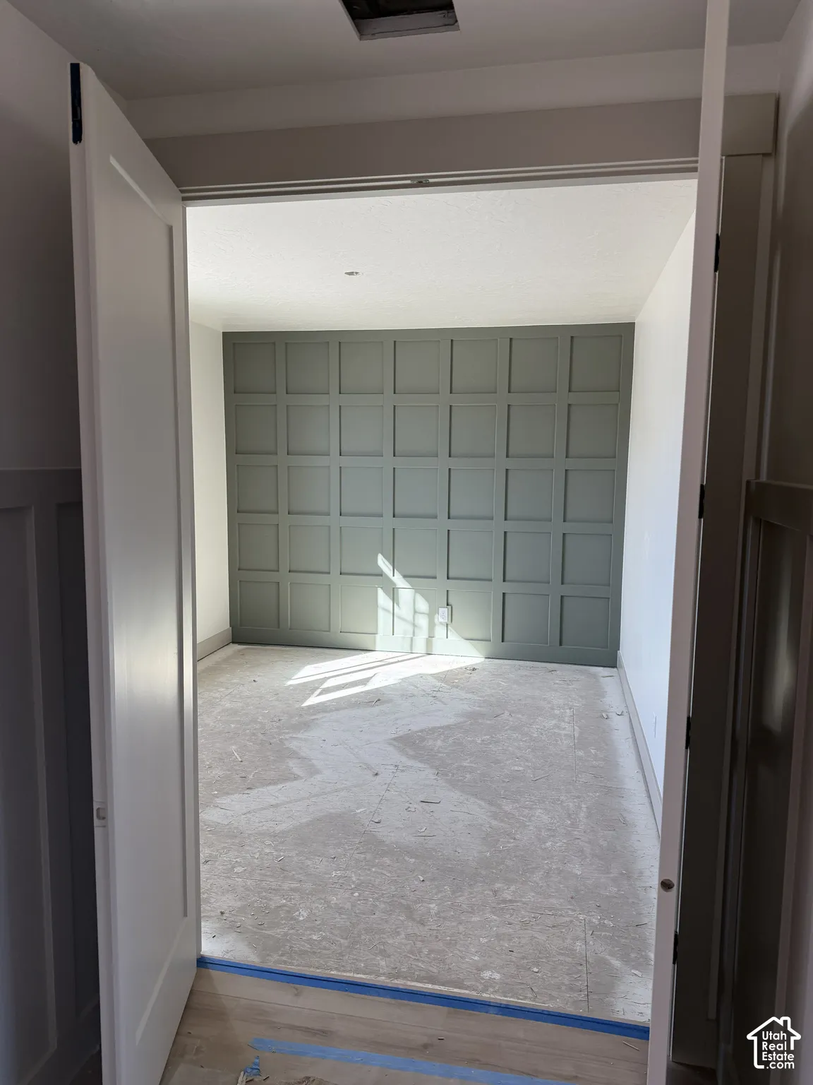 Interior space featuring double doors and a floor-to-ceiling grid-patterned accent wall in a muted sage tone