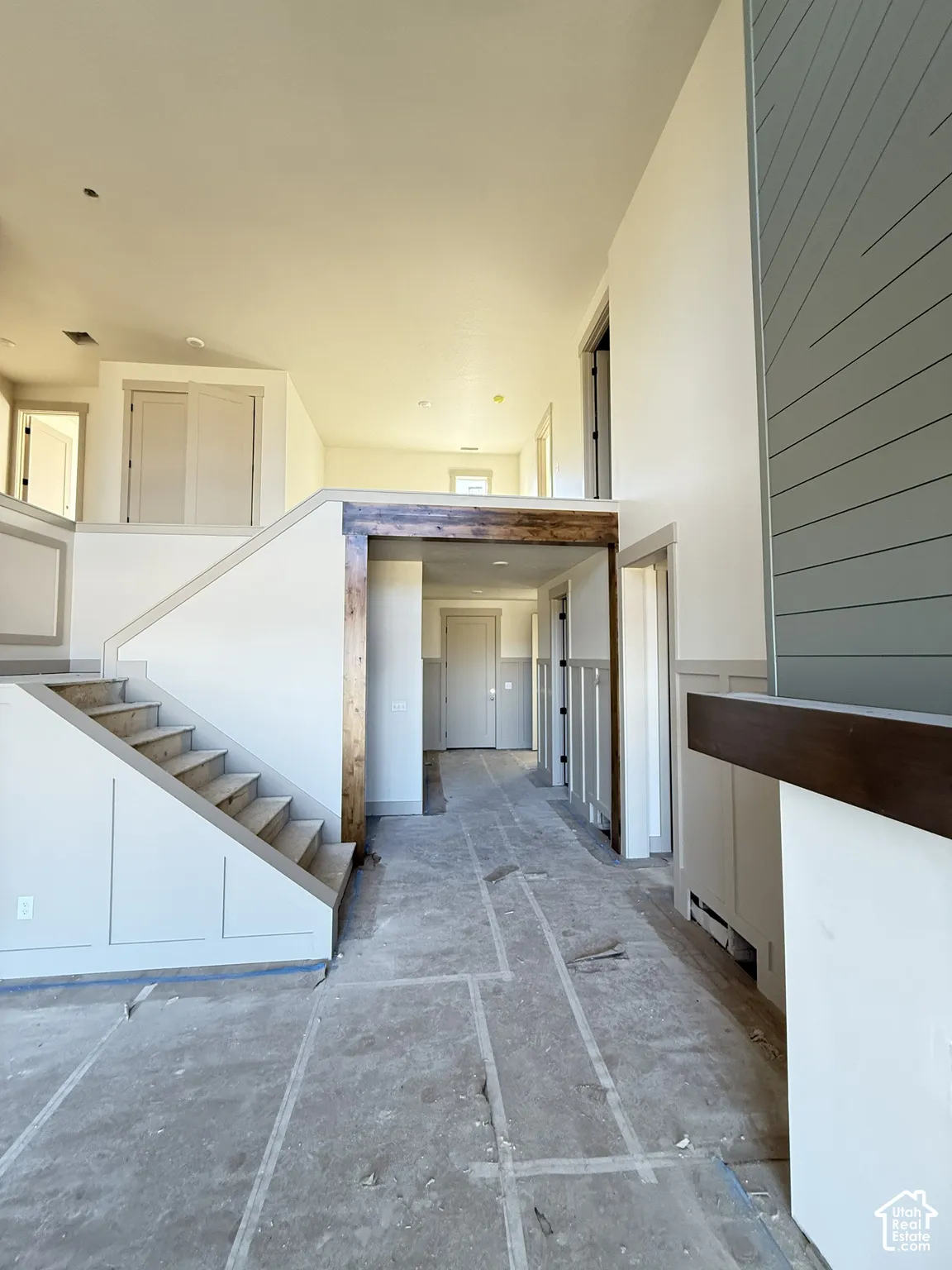 Interior featuring horizontal board-and-batten wall detailing, stained wood beam, staircase with wainscoting, and multi-level floor plan design
