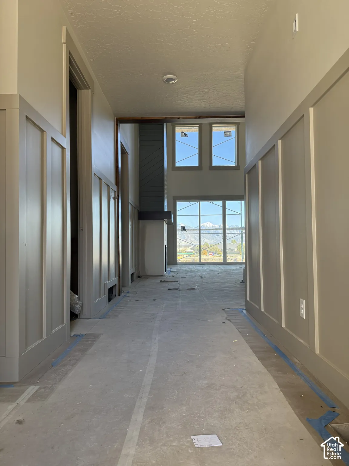 Hallway featuring board-and-batten wall paneling, full-height windows, floor-to-ceiling fireplace surround, and mountain scenery