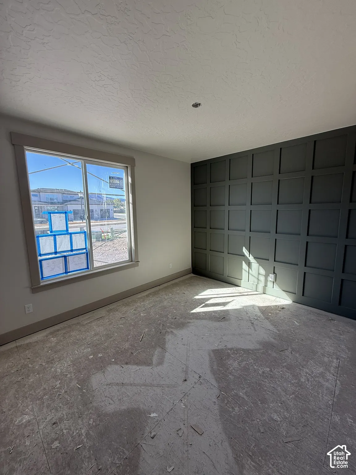 Room featuring a dark-toned grid accent wall, neutral-toned wall paint, and a sliding window with wide-profile trim
