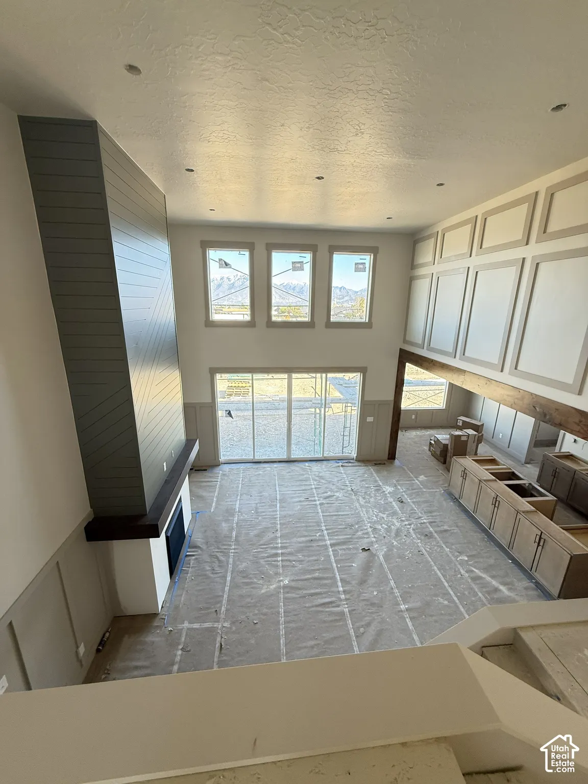 Vaulted ceilings featuring recessed lighting, floor-to-ceiling fireplace with wood-plank detailing, custom wall paneling, expansive multi-panel sliding glass doors, and cabinetry with integrated countertop surfaces
